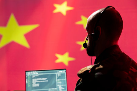 Chinese army telecommunication systems operator using radio and satellite gear, talking in headset mic. China military dispatcher managing communications networks, looking at notebook display screenの写真素材