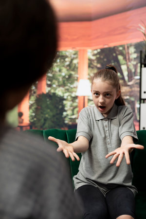 Troubled teen displays aggression and anger during therapy session, rebellious adolescent throwing a tantrum. Expert focuses on resolving issues like anger management issues and negative behavior.の写真素材