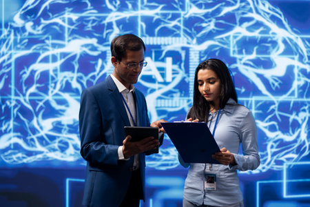 IT department coworkers solving tasks on laptop and tablet, running artificial intelligence programming scripts. Team of technicians brainstorming ways to develop AI applicationsの写真素材