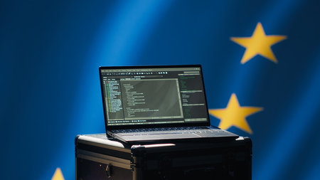 Laptop in European Union command center used by counterterrorism department to run security protocols against propaganda bots trying to destabilize democracy, isolated over EU flag, camera Aの写真素材