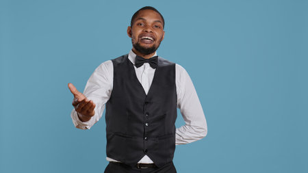 Friendly doorkeeper at five star hotel greeting guests and offering his services, excellent hospitality industry personnel. Bellhop provides luxury amenities to clients at holiday resort. Camera B.の写真素材