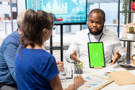 Expert shows tablet with mockup chroma key to mature couple in office, meeting for a counseling session about retirement plan options. Advisor helping senior people with their money.の写真素材