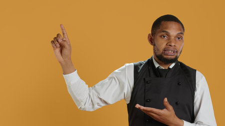 Friendly restaurant staff indicating direction to left or right sides, doing an advertisement for great customer service. Waiter showing professionalism in catering environment. Camera A.の写真素材