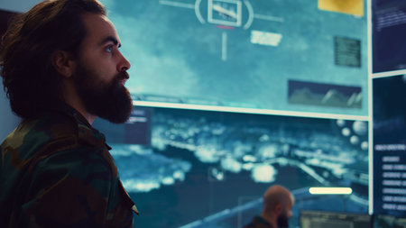 Colonel overseeing special operation to gather intelligence in control center with CCTV surveillance information on a big screen. Specialist targeting enemy military power base. Camera B.の写真素材