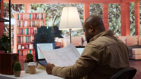 Businessman analyzing architecture blueprints for new office space layout, looking to relocate startup. Entrepreneur conducts an office hunt, business development and strategy planning. Camera B.の写真素材