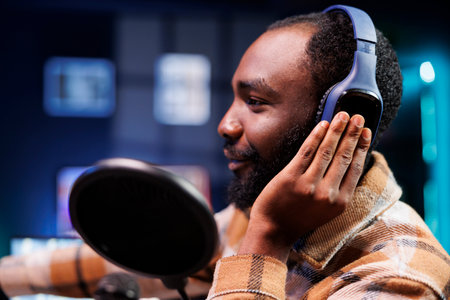 Black guy with headset is using podcast equipment to provide online advice. Male African vlogger...