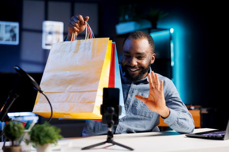 Content creator does influencer marketing, unboxing bags with internet order, showing subscribers purchases he recently got. Man presenting fans shopping acquisitions product placementの写真素材