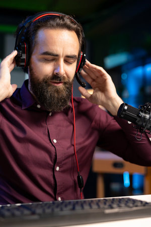 Audiophile listening to albums from favorite artist, enjoying music in studio, feeling blissful. Elated man thrilled by crisp sounding songs hearing them through headphones, closing eyes to feel goodの写真素材