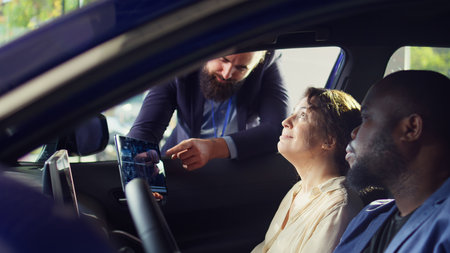 Showroom salesperson showing stat charts on tablet to clients after they finished test drive to...