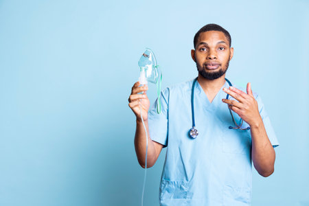 African american nurse presenting medical inhaler to help with aerosols intake, treatment for pneumonia or asthmatic patients, pulmonary disease and breathing problems. Lung condition.の写真素材