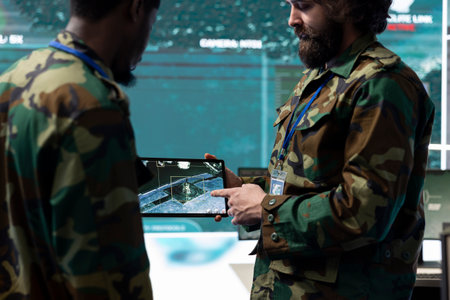 Diverse soldiers team analyzing surveillance CCTV radar imagery on a tablet, collecting real time...
