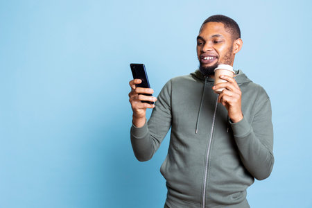 Friendly positive person receiving good news while he drinks his coffee, scrolling on social media...