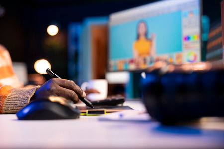 Black remote designer working from well organized home office, retouching photos on dual monitors with editing software. Young man illustrating creative career, using advanced design software.の写真素材