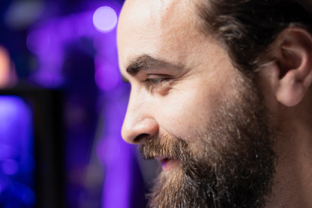 Upbeat gamer unaffected by losing match with teammates while playing competitive esports tournament. Close up of man being optimistic in spite of loss while enjoying multiplayer videogame with friendsの写真素材