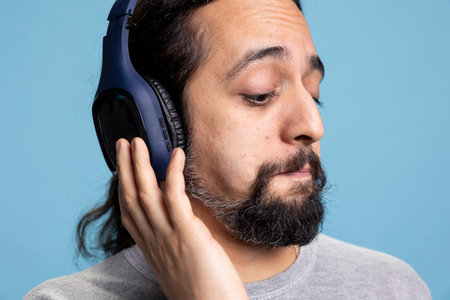 Relaxed person enjoying music on headphones expressing joy for leisure activity. Modern adult showcases enjoyment of audio entertainment and wireless gadgets in a professional studio.の写真素材