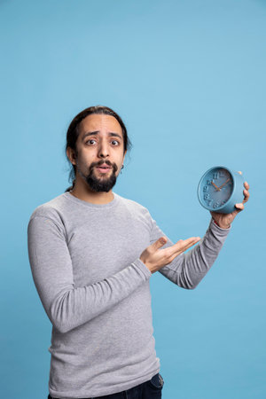 Punctual person with casual wear pointing at a wall clock on camera, looking at the hour and minutes...