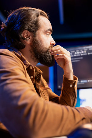 Cybersecurity professional anxiously looking at computer screen, trying to find company security loopholes and injected viruses. Programmer carefully reading lines of code on desktop PC monitorの写真素材