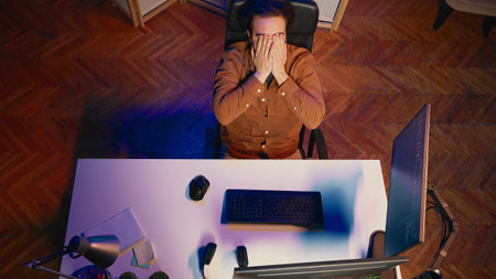 Top down view of software engineer putting face in hands in frustration while updating binary code...