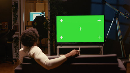 Person using chroma key video projector to binge series on subscription based streaming services. Cord cutter relaxing on couch, enjoying video on demand shows on mockup smart TVの写真素材