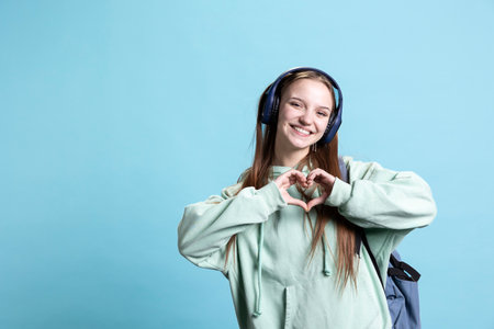 Portrait of friendly smiling woman doing heart symbol shape gesture with hands, being affectionate. Cheerful nurturing person showing love gesturing, isolated over studio backgroundの写真素材