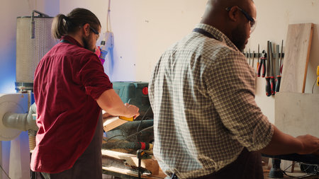 Team of woodworkers in assembly shop using sandpaper and spindle moulder for sanding wooden surface...