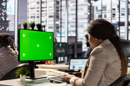 Female executive seated at her workstation with isolated copy space multitasking, analyzing financial reports to support strategic business goals and decision making processes.の写真素材