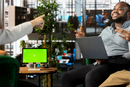 Isolated screen tablet next to smiling employee chatting with coworker during business meeting. Mockup device next to jolly worker having fun with colleague while doing research analysisの写真素材