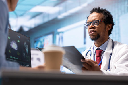 Male physician doing an x ray diagnostics scan interpretation during check up visit, discussing about recovery treatment in cabinet. Doctor examining radiography test results for a patient.の写真素材