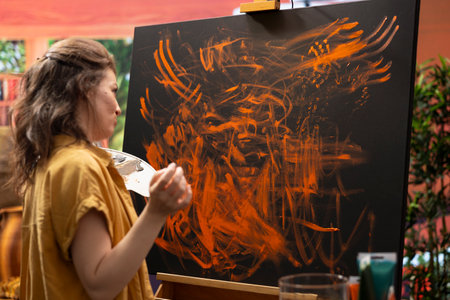 Painter works with finger painting technique on her latest artwork piece, contemporary art studio buzzes with creativity. Artist uses vibrant colors and for a modern paintwork design.の写真素材