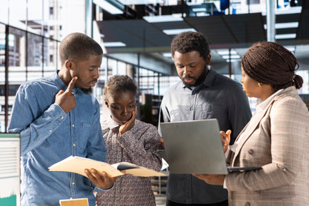 African American team collaborates on a financial planning project in a corporate office,...