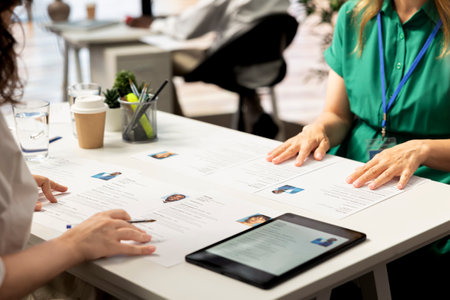 HR staff members using tablet to look at CVs and do background checks to potential job applicants. Headhunters use device to read resumes, attracting qualified candidates for vacant startup positionの写真素材