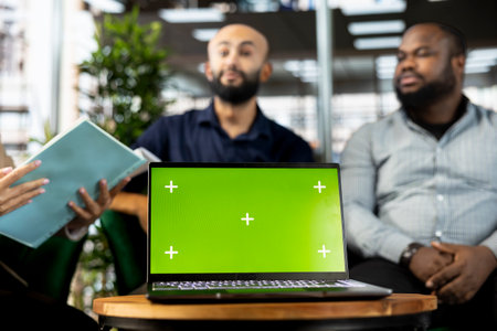Colleagues preparing for business meeting to plan project, using green screen laptop to design marketing strategy. People doing research analysis for startup organization using mockup notebookの写真素材