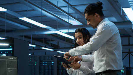 Team of technicians working on tablets in data center used for managing gear energy consumption....