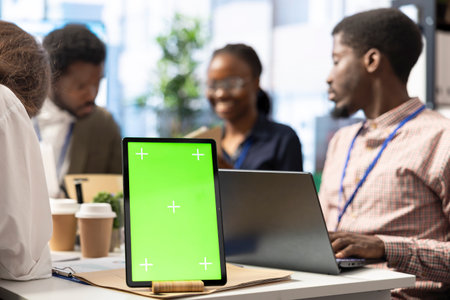 Marketing team reviews performance metrics next to green screen on tablet, leveraging big data...