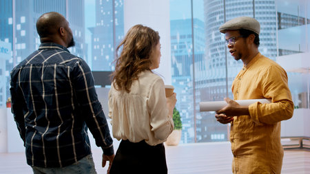 Business clients discussing design and layout of a new office space with the broker, reviewing a...