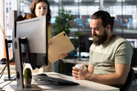 Tired company worker caught falling asleep at desk in office by manager while doing research for team project. Exhausted man sleeping in front of computer screen in workplace, caught by team leaderの写真素材