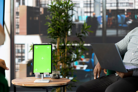 Isolated screen tablet next to manager working on laptop in office, coordinating company...