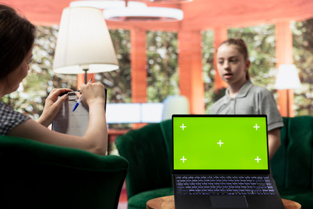 Adolescent in therapy session focused on mental health next to isolated mockup screen, works on emotional well being. Psychotherapist supporting the teen to manage anxiety and depression.の写真素材