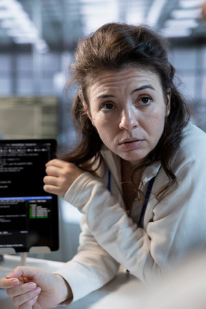 Technician using tablet to implement cybersecurity measures to protect data center assets. Woman in server hub monitoring and analyzing metrics with device to enhance operational effectivenessの写真素材