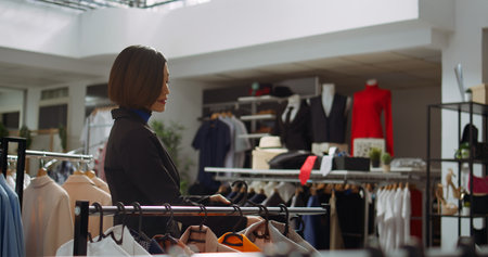 Fashion boutique worker sorting all two piece sets on hangers in the store, creating a chic trendy display with the new collection. Arranging the designer made merchandise. Camera B.の写真素材