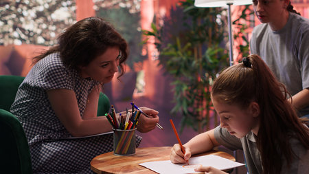 Therapist guiding a troubled teen through creative therapy system, using drawing as a method to manage intrusive thoughts and mental health. The mother observes, offering emotional support.の写真素材