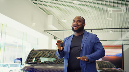 Happy customer in car dealership excited after taking advantage of sale offer presented by salesman, enjoying finalized purchase. Jolly client shaking automobile keys, ecstatic about deal, camera Bの写真素材