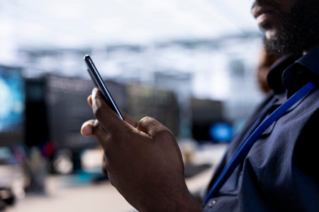 Man in data center texting friends on smartphone, taking break from creating technical documentation for software applications. IT expert using mobile phone while working in server room, close up shotの写真素材
