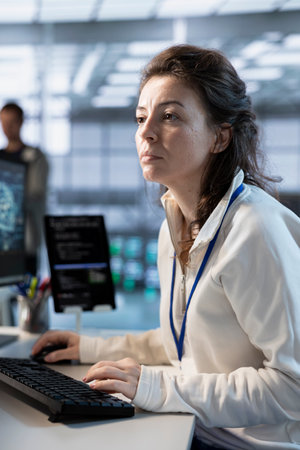 Programmer in server hub facility ensuring compliance with industry standards and regulatory requirements. Data center IT specialist conducting security audits to protect against phishing attacksの写真素材