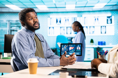 African american physician and patient engaging in detailed consultation with diagnostic tools, professional care and wellness. Doctor gives advice for disease prevention to young man.の写真素材