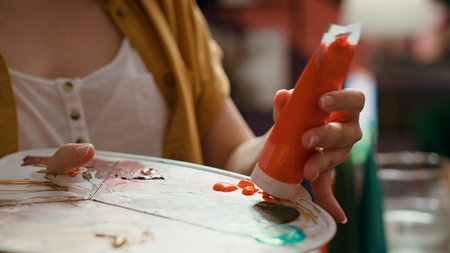 Woman with talent painting a rustic masterpiece and using fabric to clean her brush after changing the color. Artist feeling inspired to try a new painting technique in art and craft workshop. Camera A.の写真素材