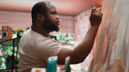 Skilled artist painting an artwork with colorful paints mixed on a palette, creating a beautiful creative paintwork with a painting technique in his atelier. Painter mixing watercolor.の写真素材