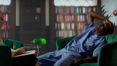 African American nurse trying to cope with stress and loss during counseling, seeking support in a therapy session. Medical assistant opening up about hard patient cases at work. Camera B.の写真素材