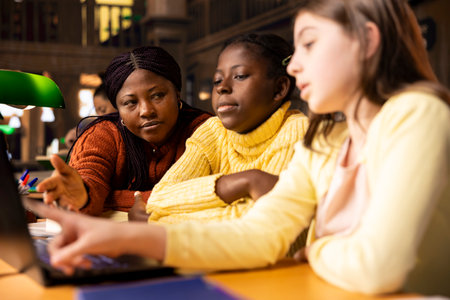 Elementary school professor engaging with girls students during private lessons, provides tutoring...