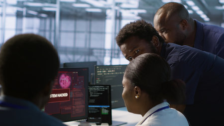 Team of engineers in server hub trying to protect gear from hacker stealing sensitive information. Data center coworkers struggling to erase virus after seeing security breach notification, camera Aの写真素材